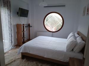 a bedroom with a white bed with a round mirror at ΑΡΧΟΝΤΙΚΟ ΜΑΝΤΕΙΟ in Manteio +25 photos