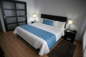 1 dormitorio con 1 cama grande con sábanas azules y blancas en Hotel Internacional La Triada en Bucaramanga
