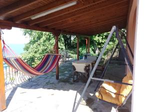 eine Veranda mit zwei Hängematten und einem Tisch auf einer Terrasse in der Unterkunft Με Θεα!! in Stomio