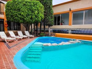 a large swimming pool with chairs and a building at Hotel Paseo de la Presa in Guanajuato