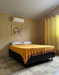 a bedroom with a bed with a yellow blanket on it at Recanto Primavera Ubatuba in Ubatuba +142 photos