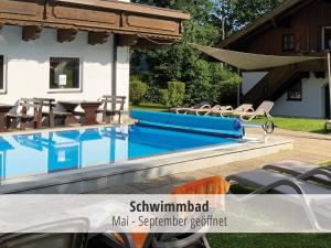 a swimming pool with chairs and a house at Ferienwohnung Hauzenberg mit Pool & Sauna in Hauzenberg
