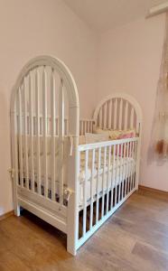 two white cribs in a room with wooden floors at Sunny in Trnava