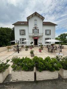a large white building with a patio with tables and chairs at Logis Hôtel & Restaurant Le Parcey in Parcey