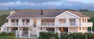 duży biały dom z brązowym dachem w obiekcie The Beach House w mieście Port Alfred