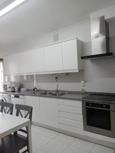 a kitchen with white cabinets and a sink and a table at House Moledo sea view in Moledo