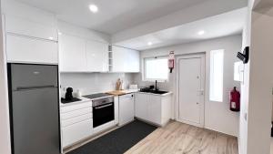 a white kitchen with white cabinets and a window at The Cate House - Casa renovada a 3 minutos do Centro Histórico in Lagos