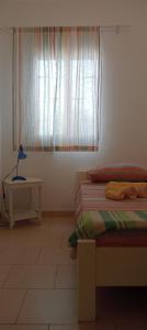 Zimmer mit 2 Betten, einem Fenster und einem Tisch in der Unterkunft Farfalla in Vila do Maio