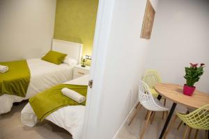 a bedroom with two beds and a table and chairs at Pregonero Urban Suites - Verde in Soria