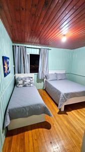 two beds in a room with blue walls and wood floors at Casa Privativa no Centro de Urubici - Casa Doce Luar in Urubici