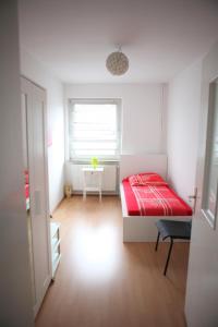 um pequeno quarto com uma cama vermelha e uma janela em White House Bochum Ehrenfeld em Bochum