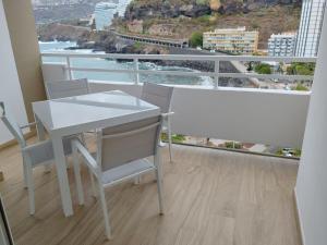 Una mesa y sillas blancas en una habitación con balcón. en Le Terrazze 7, en Puerto de la Cruz