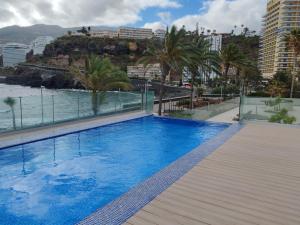 una piscina en la azotea de un edificio con palmeras en Le Terrazze 7, en Puerto de la Cruz
