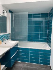 a blue tiled bathroom with a tub and a sink at Ker Bihanic classée 3 étoiles in Lézardrieux