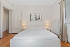 a large white bed in a white room with two lamps at Elegant 3BR Home in Prime Limpertsberg Location in Luxembourg