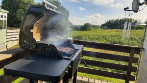a grill on a deck with a view of a field at Lochview Retreat Caravan in Balminnoch