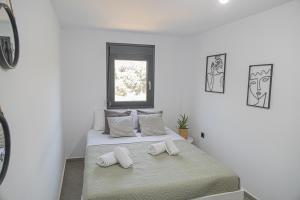 a white bedroom with a bed with two towels on it at Ammira Mare Apartment in Agia Pelagia +32 photos
