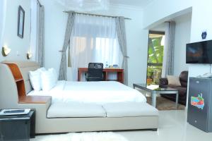 1 dormitorio con 1 cama, escritorio y TV en Mowicribs Hotel and Spa en Entebbe