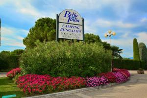 a sign for a car dealership in a bed of flowers at Camping Bella Italia in Peschiera del Garda