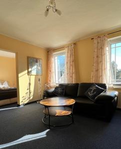 a living room with a black couch and a table at Hotel-Pension Zur Mole in Wiek auf Rügen 