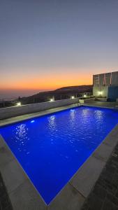 a large blue swimming pool with a sunset in the background at Ayla Chalets in Amman +8 photos