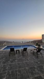 a swimming pool with two chairs and a table next to it at Ayla Chalets in Amman