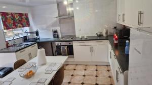 a kitchen with white cabinets and a table in it at Amani Bungalow in Brandon