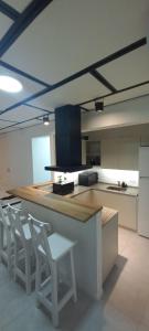 a kitchen with a counter and white chairs in it at Dpto Temporario La Rosada in Corrientes