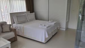 a white bedroom with a bed and a chair at Yasos By The Sea in Çeşme