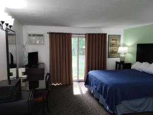 a hotel room with a bed and a sliding glass door at Tri Terrace Motel in West Branch