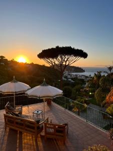 a sunset over a patio with two umbrellas at Resort Terme La Pergola in Casamicciola Terme