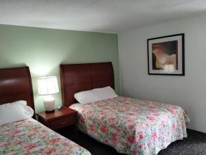 a hotel room with two beds and a table with lamps at Tri Terrace Motel in West Branch