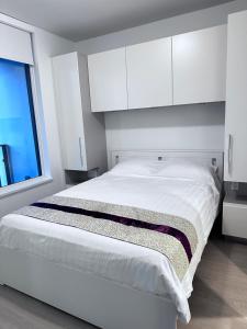 a white bedroom with a large bed with white cabinets at Monthly stay-Relocation Special-New condo at Metrotown in Burnaby