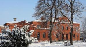 un gran edificio de ladrillo rojo con nieve en el suelo en Resursa, en Żyrardów