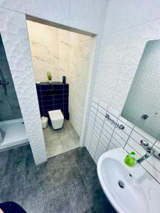 a white bathroom with a sink and a toilet at Sunrise Apartamenty in Chocicza