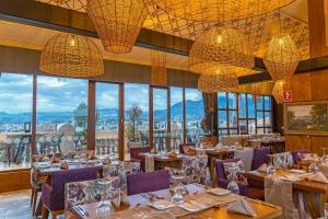a restaurant with tables and chairs and large windows at Hotel Cruz del Vado by Art Hotels in Cuenca