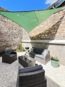 a patio with two couches and a green umbrella at Le Ptit Gite de Chablis - Maison avec Cour en Centre-Ville in Chablis