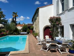 a swimming pool with chairs and a table next to a building at Le Relais du Puy in Saint-Fulgent