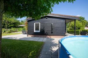 a small house with a swimming pool in front of it at Jamies Cottage Warmenhuizen nu met airco in Warmenhuizen