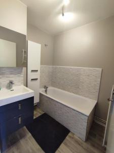 a bathroom with a bath tub and a sink at LENS, Bel appartement lumineux spacieux en centre ville 3 chambres in Lens