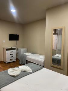 a bedroom with two beds and a dresser and a mirror at POUSADA AREIAS DE PAJUÇARA in Maceió