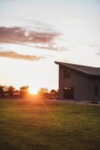 a house in a field with the sunset in the background at Viesu māja Daugava in Salaspils +4 photos