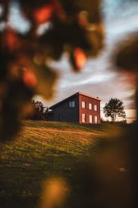 a red building on a field with a house at Viesu māja Daugava in Salaspils