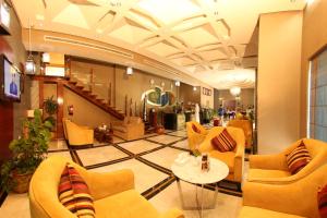 a lobby with yellow chairs and a table in a building at Coral Olaya Hotel in Riyadh