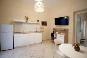 a kitchen with white cabinets and a table and a tv at RelaxTime Casa Vacanze in Palermo