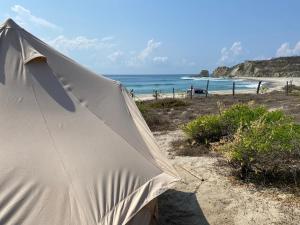 a tent on the beach with the ocean in the background at Natevo Surf Camping in Barra