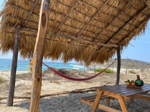a picnic table under a straw umbrella on the beach at Natevo Surf Camping in Barra