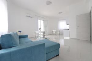 a living room with a blue couch and a kitchen at B&B La Dea in Marzamemi