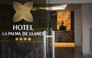 
a man looking at his cell phone in front of a building at Hotel La Palma de Llanes in Llanes

