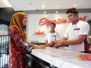 una mujer y dos hombres parados en un mostrador en Signature Hotel @ Bangsar South en Kuala Lumpur
